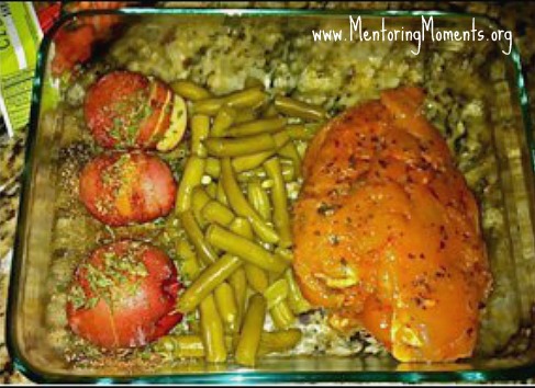 Casserole dish with three small red potatoes drizzled with olive oil and topped with parsley laying next to green beans laying next to a boneless skinless chicken breast seasoned with Italian seasoning.