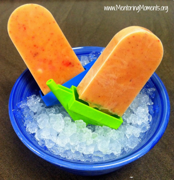 Peach-Strawberry homemade popsicles resting in a bowl of ice.